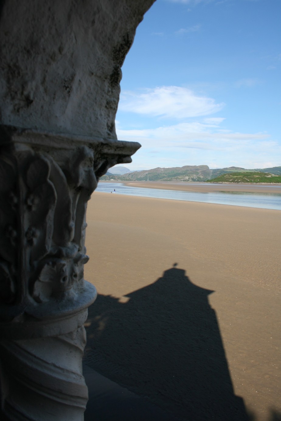 Shadow from the tower falling over wet sand in Portmerion