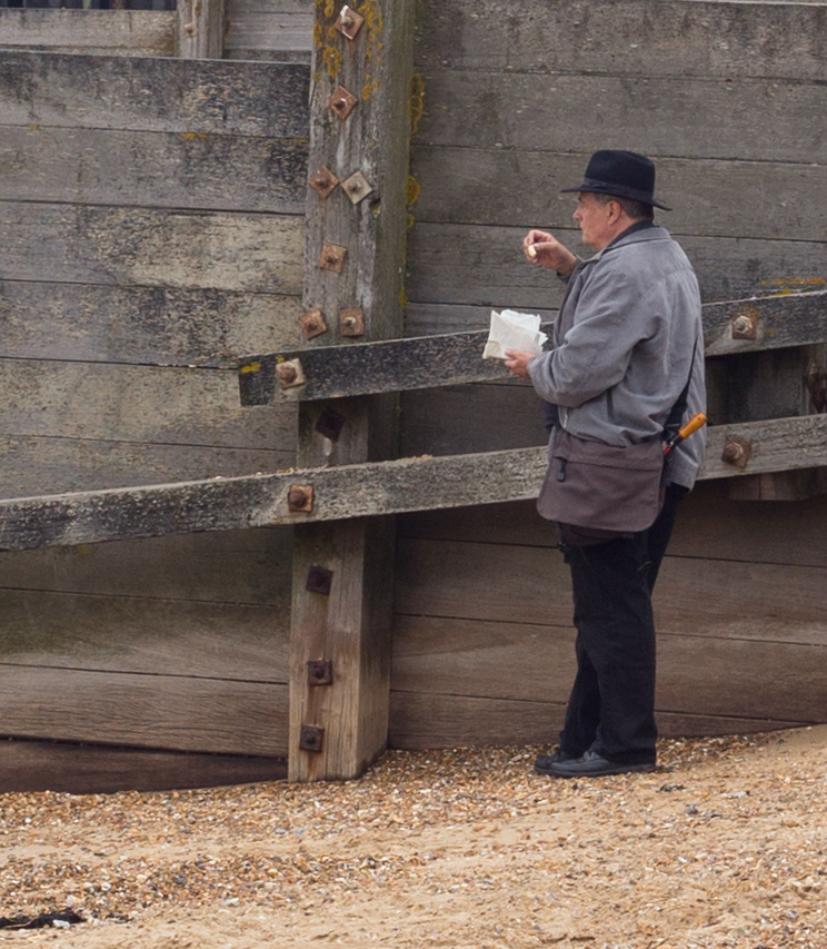 Covert chip-eating on the beach, hiding beside a groyne - but who is he hiding from . . .