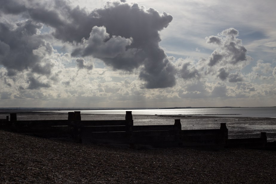 At last by late afternoon the solid grey sky began breaking up and shafts of silvery light played across the sea.