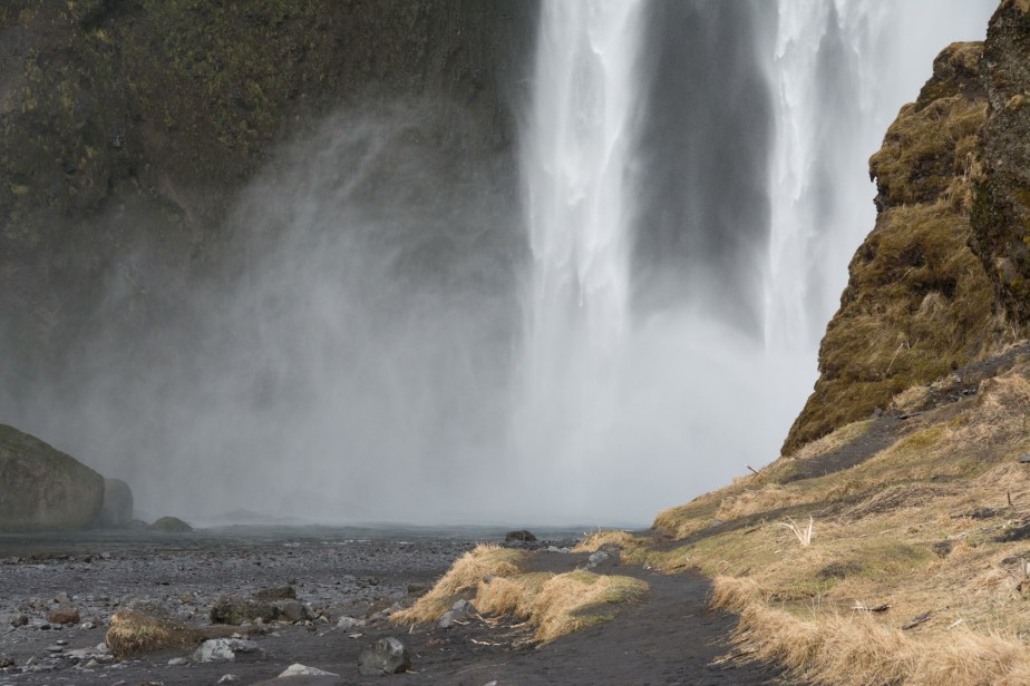 The back spray flies way out to the side as the water hits the flat ground below, making a dense white mist.